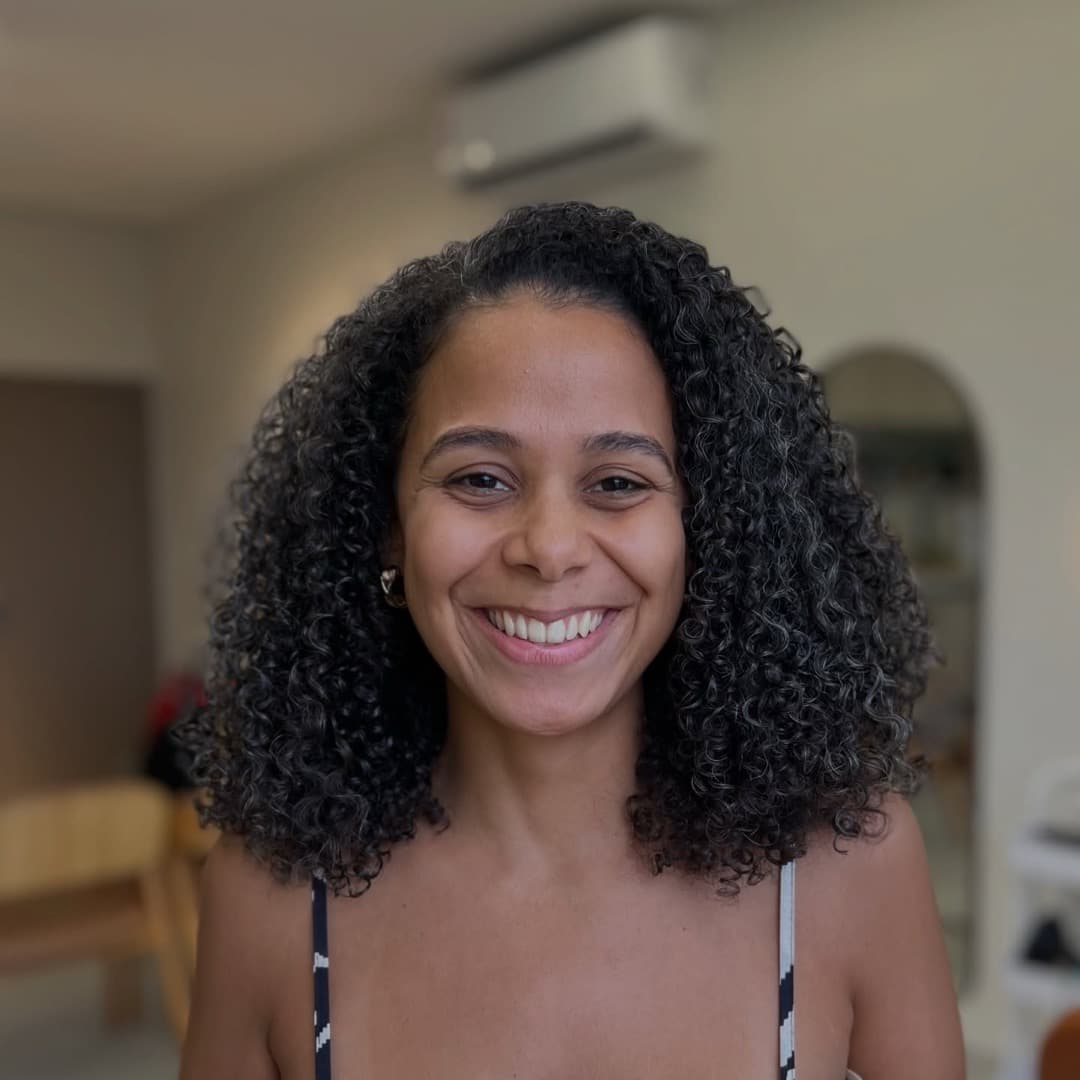 Cliente sorridente do Studio Raízes com cachos longos