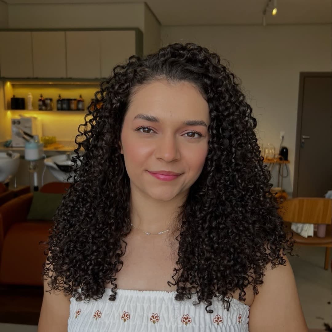 Cliente do Studio Raízes com cachos definidos abaixo dos ombros